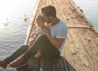 En man och hans dotter sitter på en brygga