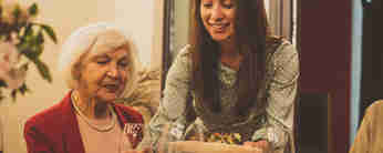 En bild på en äldre dam och en yngre tjej vid ett middagsbord