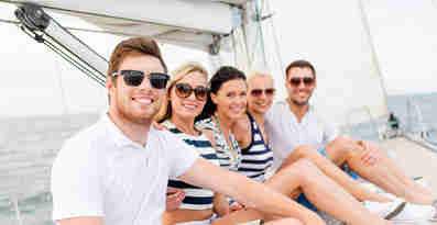 En grupp människor på en segelbåt ler och tittar in i kameran