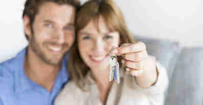 En man och en kvinna ler och håller upp en nyckel