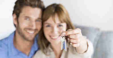 En man och en kvinna ler och håller upp en nyckel