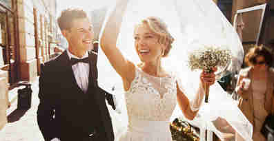 En glad man och en glad kvinna i bröllopskläder