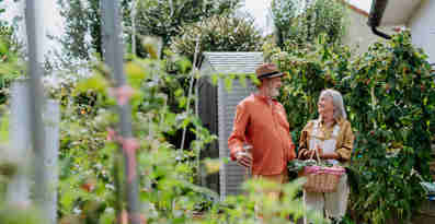 En man och en kvinna står i sin trädgård