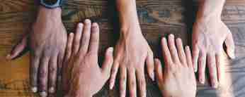 Fyra händer med olika hudfärg ligger bredvid varandra